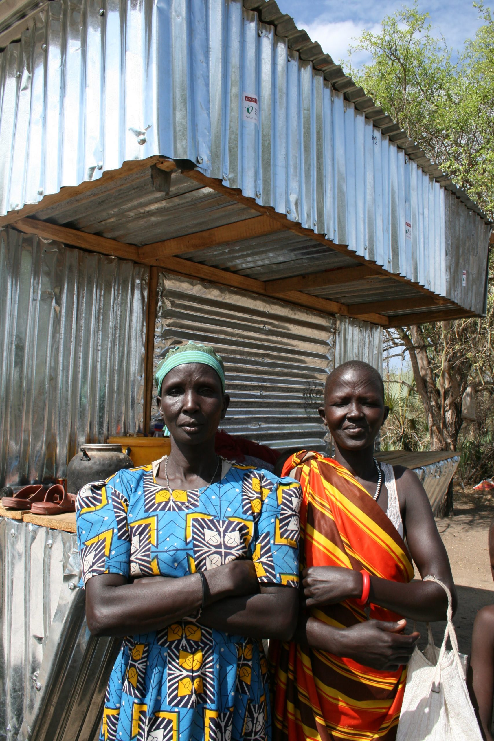 Two women stand in front of a metal stall.